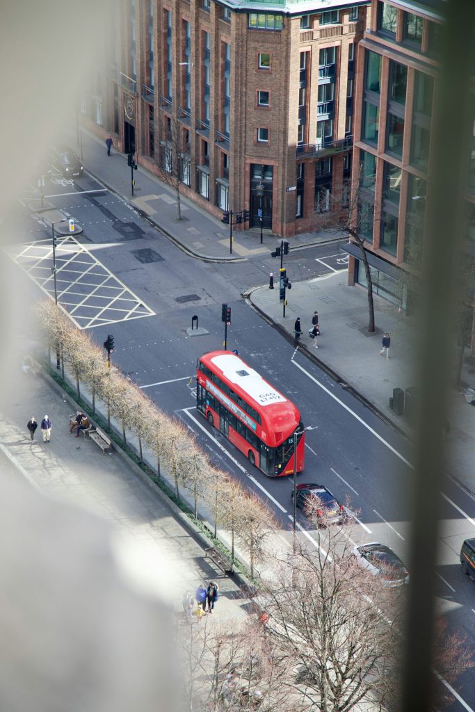 a red bus driving down a street next to tall buildings