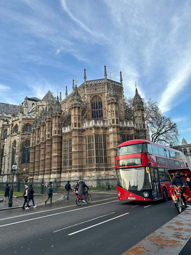 a red double decker bus driving past a tall building