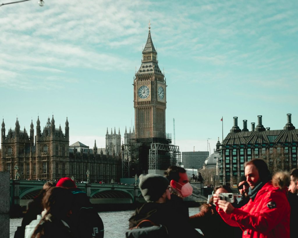 a group of people taking pictures of a clock tower with Big Ben in the background
