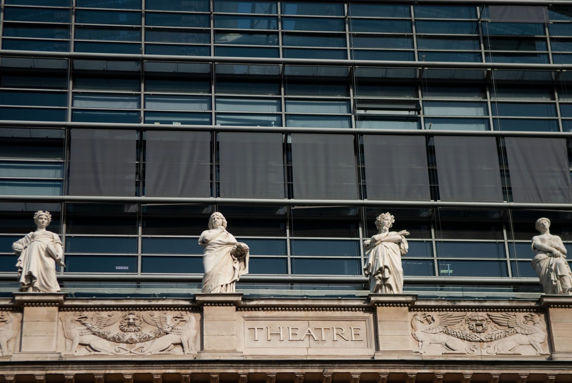Low-angle shot of a theater facade in Lyon, France, adorned with classical sculptures